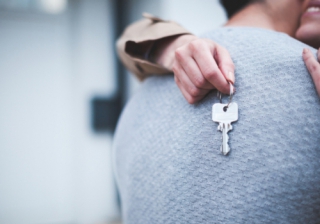 a couple hugging, one holding a house key